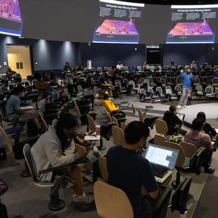 Students engaged during lecture in in-the-round lecture hall.